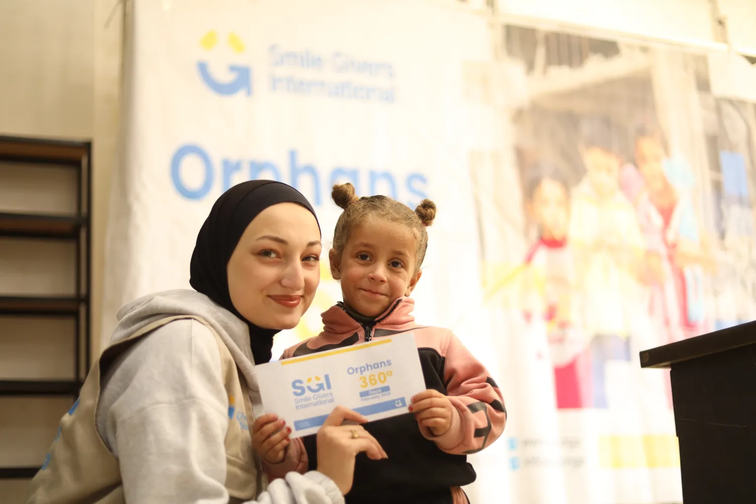 SGI worker with orphan child holding Orphans 360 card