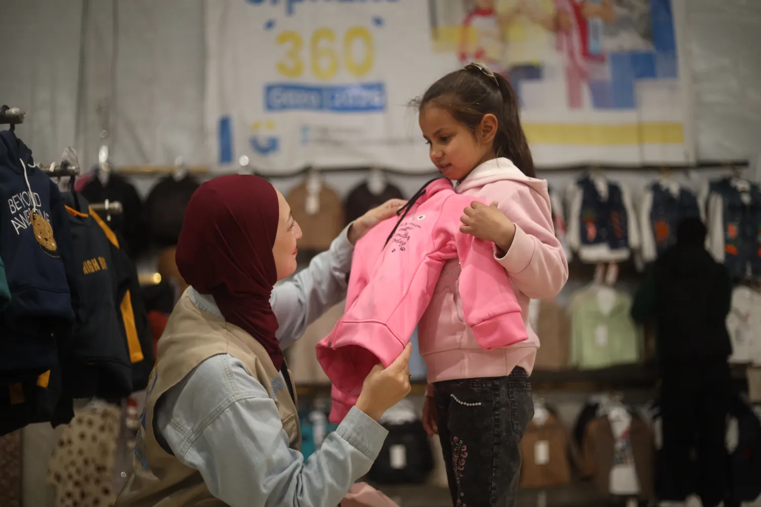 SGI worker helping orphan girl try on warm clothing